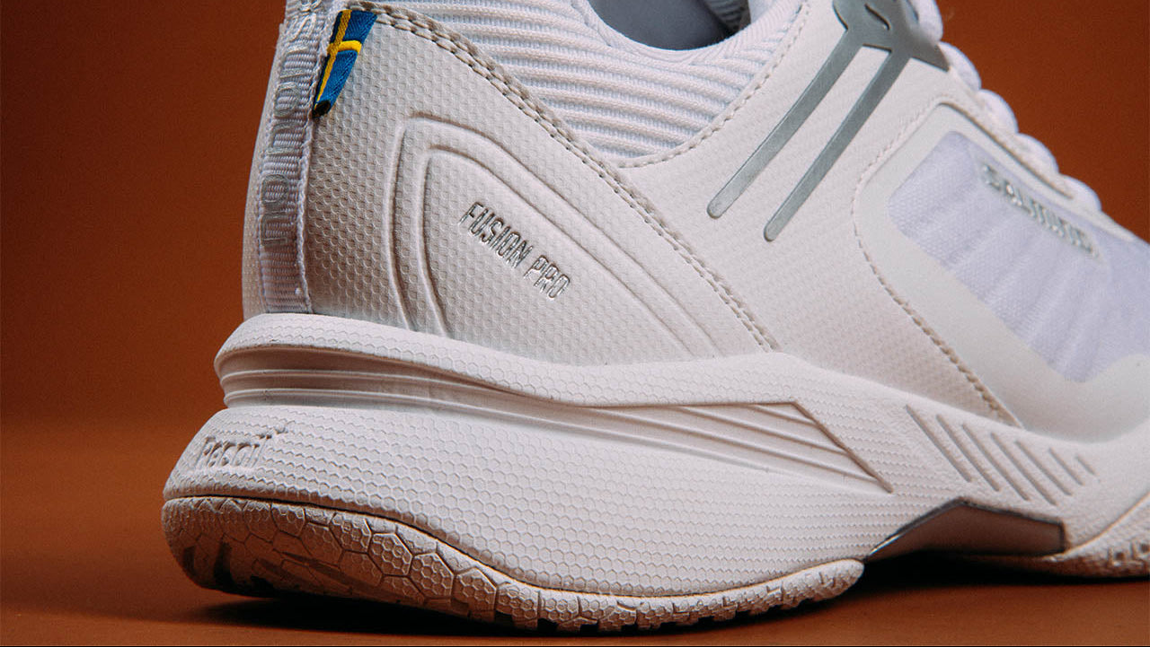 White athletic Salming shoe model Fusion Pro with branding on a brown background