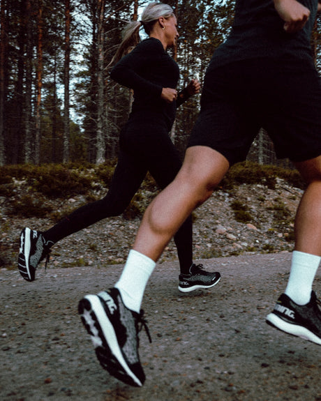 Two people running on a path in a forested area