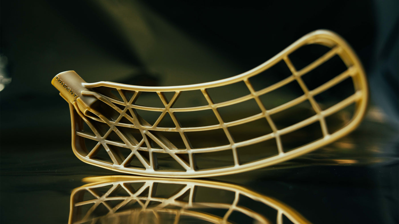 Gold floorball blade on a reflective surface with a dark background