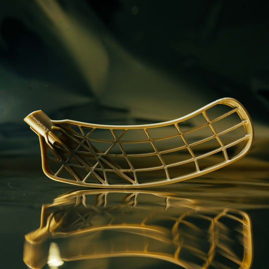 Gold floorball blade on a reflective surface with a dark background